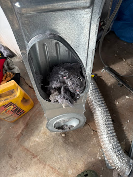 Severely clogged dryer vent transition box packed with compressed lint photographed during an Express Xpert dryer repair and vent cleaning service call in Miami, Miami-Dade County, FL