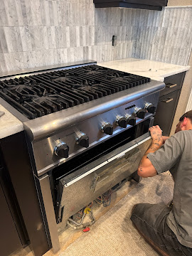Express Xpert technician servicing a stainless-steel premium gas range cooktop with the burner cap removed in an Aventura, Miami-Dade County, FL home kitchen