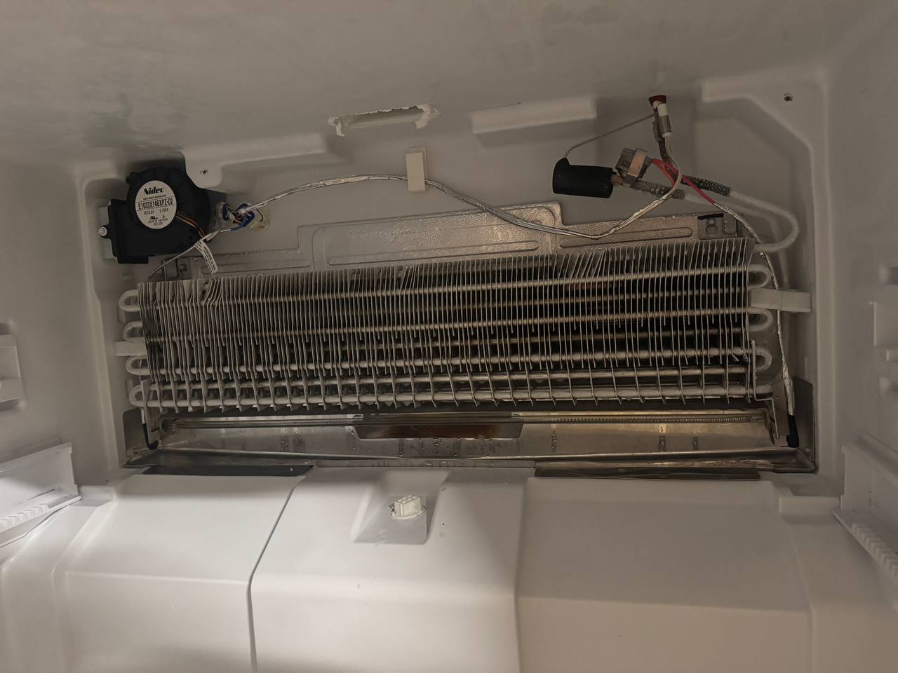 Refrigerator evaporator coil and defrost system exposed during an Express Xpert refrigerator repair in Miami-Dade County, FL — defrost heater, evaporator fan motor, and water solenoid visible