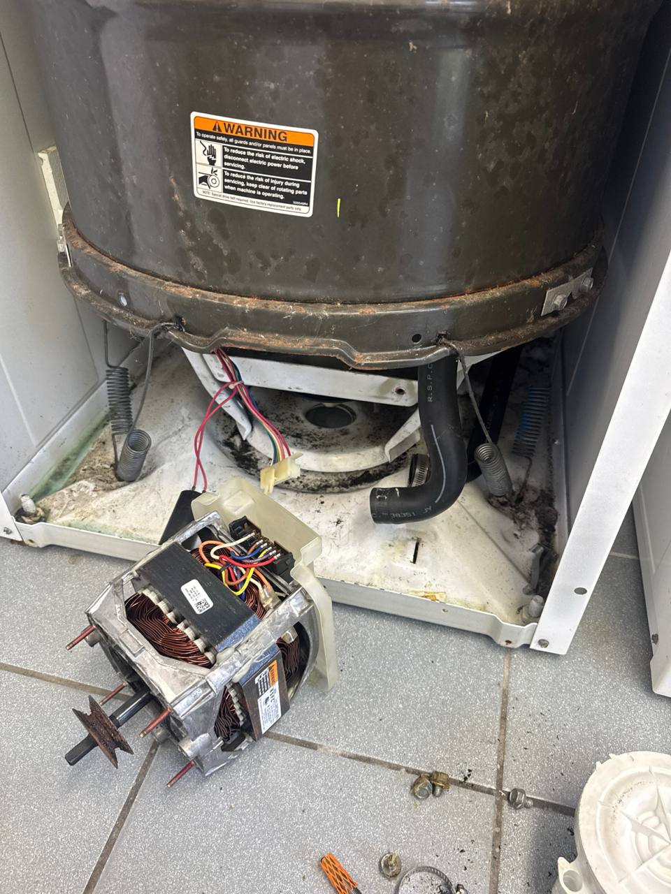 Top-load washing machine cabinet tipped open with the drum, drive motor, and drain pump removed during an Express Xpert washer tear-down repair in Fort Lauderdale, Broward County, FL